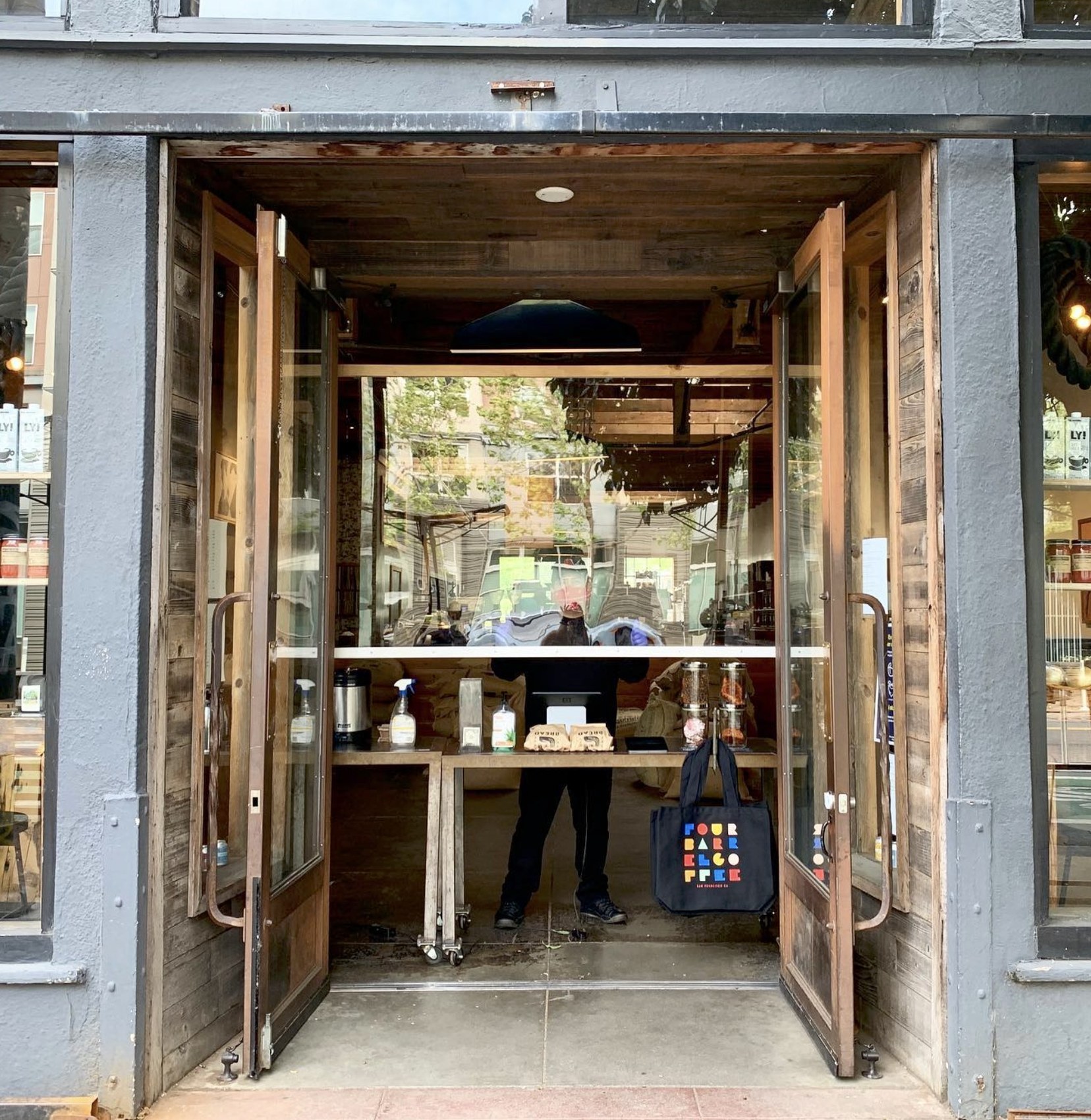 The open storefront doors at Four Barrel Coffee with the counter and retail shelves